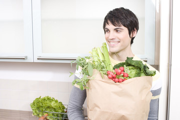 junger mann tr&auml;gt einkauf