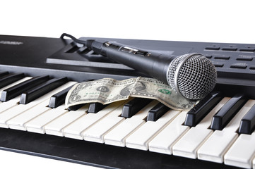 A microphone and dollar lying on the keys