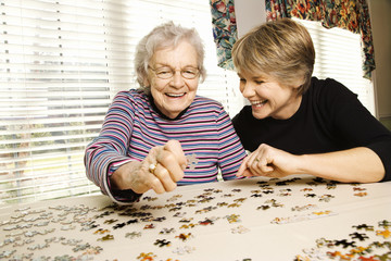 Elderly Woman and Younger Woman Doing Puzzle - 19891154