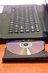 Closeup image of a laptop and a CD / DVD disc