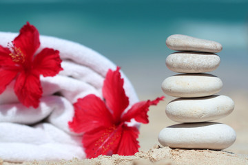 Stack of white stones and towel with red flower in beach spa