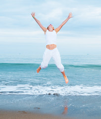 Obraz premium happy young woman is jumping in the beach