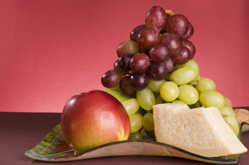 Fruits and cheese lying in a plate.