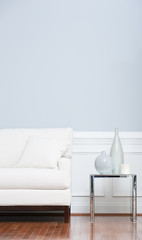 White Sofa and Glass End Table Against Blue Wall