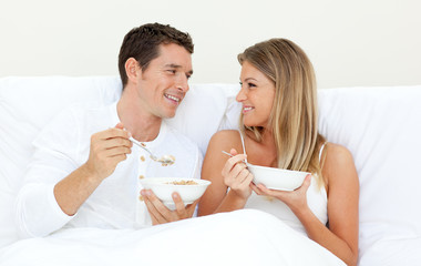 Obraz na płótnie Canvas Affectionate couple having breakfast lying on their bed