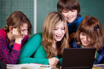 schüler sitzen zusammen vor einem laptop