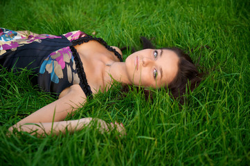 Young beautiful woman lying on a green grass