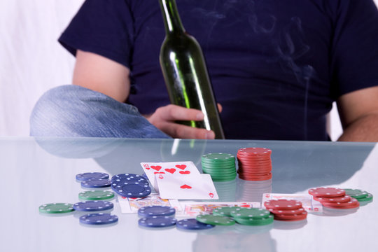 Man Holding a Whiskey Bottle on a Poker Table