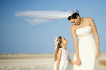 Fototapeta na wymiar Bride and Flower Girl on Beach