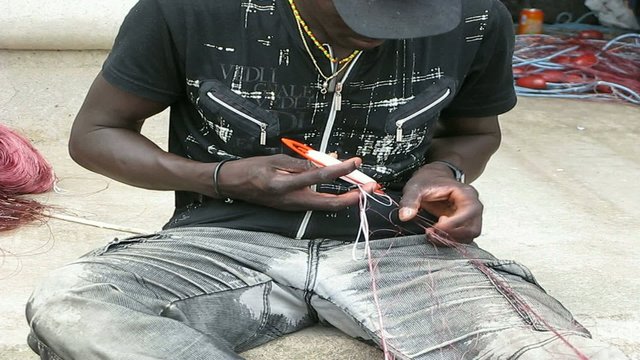 HOMBRE REPARANDO LAS REDES DE PESCA