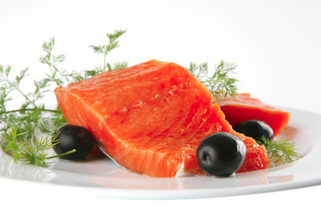 pink smoked salmon on white plate with olives