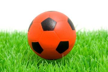 Orange soccer ball on grass over white background