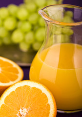 Orangensaft in Karaffe mit Orangen und Weintrauben