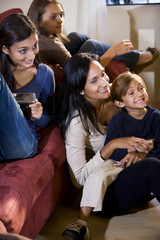 Mother and three children sitting together on couch watching TV