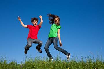 Kids jumping, running against blue sky