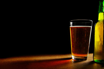 pint glass of beer and bottle, oin black background