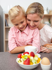 Adorable little girl eating fruit with her mother