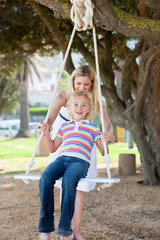 Happy mother pushing her daughter on a swing