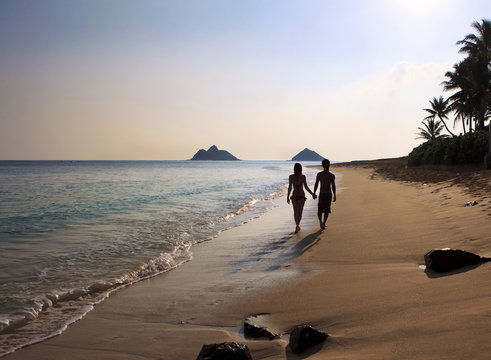 Silhouette Of Couple Jumping In The Air At A Hawaii Beach