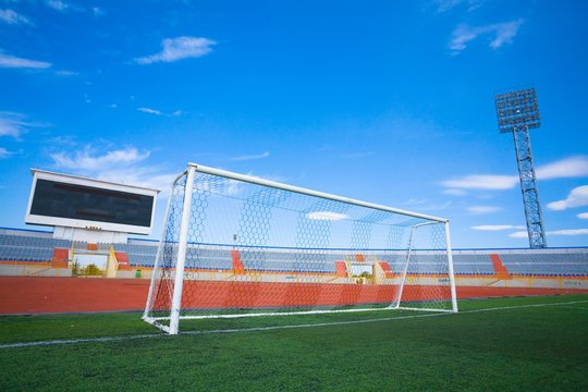 STADIUM - Football field with goal and tablo on blue sky