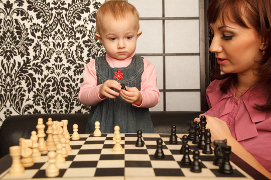 Mother and her little doughter near chess board