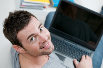 Smiling casual man working on laptop
