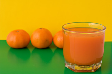 glass of fresh juice on green and yellow background