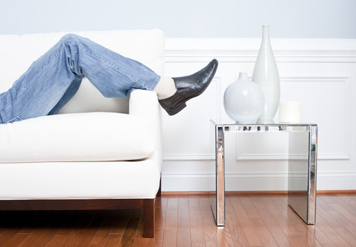 Man's Legs Reclining On White Couch