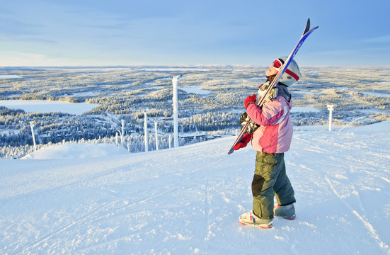 girl-skier watching the sunrise  at a ski resort in Finland