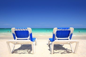A pair of chaise lounges on a tropical beach