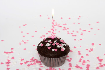 Schokoladenmuffin mit Kerze und Zuckerherzen