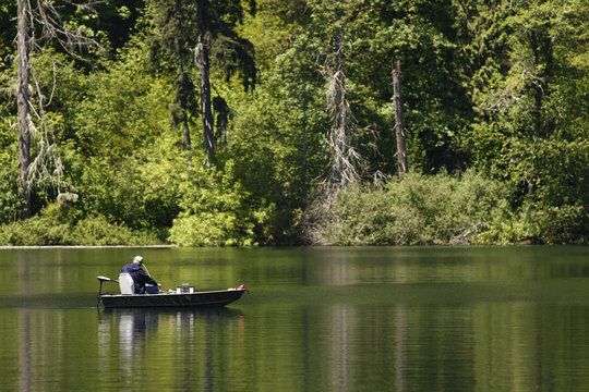 Man in a boat fishing on a lake.
