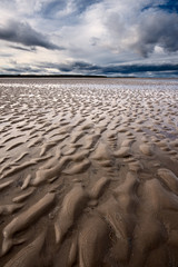 Fototapeta na wymiar Beach textures at low tide with dramatic sky