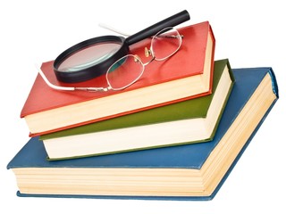 Glasses and magnifying glass on a pile of books