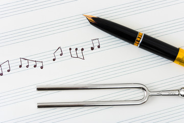 Pitchfork and pen on music sheet