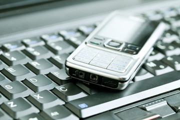 Business concept - mobile phone over laptop keyboard