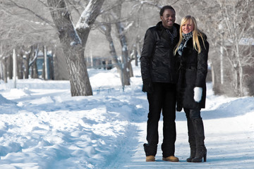 Fototapeta na wymiar Romantic multi-etnic couple is walking in the winter park