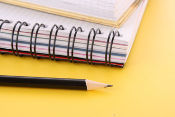 Notebook with pencil on the yellow background