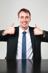 Mann beide Daumen hoch am tisch