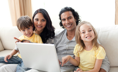 Jolly family using laptop on sofa