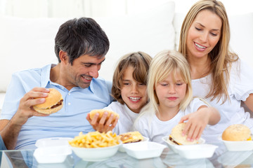 Obraz na płótnie Canvas Joyful family eating hamburgers