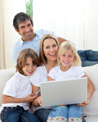 Fototapeta na wymiar Cute dzieci z ich rodzicami przy użyciu komputera przenośnego