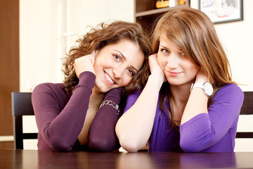 portrait of two girls sitting on a kitchen table