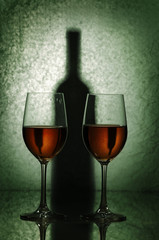 glasses of wine and shadow of a bottle on a green background