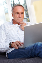 mature man with laptop, thinking