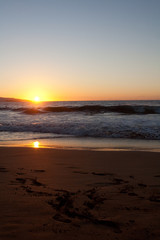 Sunset on the beach with foot prints in the sand