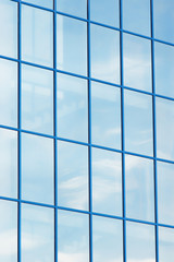 row of building windows in blue frame and cloud reflection
