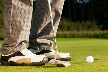 Golf player putting the ball in the hole