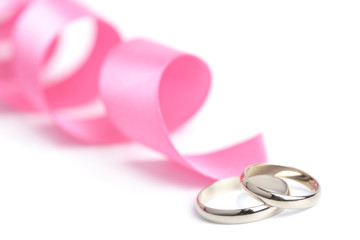 Gold wedding rings and pink ribbon isolated