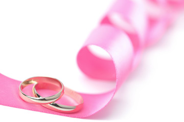 Gold wedding rings over pink ribbon isolated